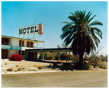 Load image into Gallery viewer, Photograph by Richard Heeps. A derelict motel office sits on a dusty American road. A large palm tree sits at the front of the office's walkway.