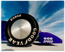 Load image into Gallery viewer, Photograph by Richard Heeps. This photograph has the tyre and the very front tip of a drag car. The car's name is written on the front end "God Speed". Behind the car are white vertical clouds shooting through a blue sky.