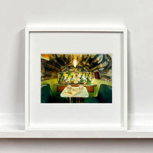 Load image into Gallery viewer, White framed photograph by Richard Heeps. Inside a trailer, there is a fixed table and chairs with two tea cups and saucers on the table. Behind on the shelf is a tea set and a doll dressed as a bride.