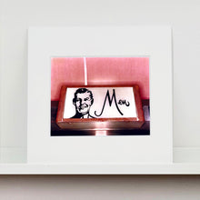 Load image into Gallery viewer, Mounted photograph by Richard Heeps. A kitsch Men's toilet sign. The sign has the word Men alongside an outline of 1950s man. The sign sits in a wooden frame and sits against a pink tiled wall.