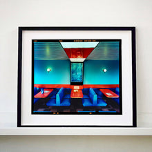 Load image into Gallery viewer, Black framed photograph by Richard Heeps. The inside of a Wimpy restaurant. Blue upholstered double seats pinned to the floor and separated by striking red tables. The walls are blue with a blue picture of trees with a black surround aligned with the middle table.