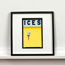 Load image into Gallery viewer, Black framed photograph by Richard Heeps.  At the top black letters spell out ICES and below is depicted a 99 icecream cone sitting left of centre against a sherbert yellow coloured background.  