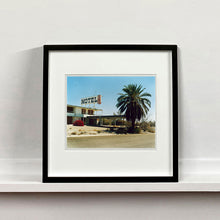 Load image into Gallery viewer, Black framed photograph by Richard Heeps. A derelict motel office sits on a dusty American road. A large palm tree sits at the front of the office's walkway.
