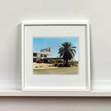 Load image into Gallery viewer, White framed photograph by Richard Heeps. A derelict motel office sits on a dusty American road. A large palm tree sits at the front of the office's walkway.