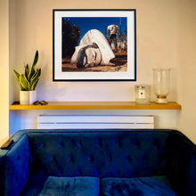 Load image into Gallery viewer, In situ black framed photograph by Richard Heeps. In the foreground of the photograph is a broken off head of a giant fibreglass sculpture of a cowboy (a Muffler Man). In the background set in a deep blue sky is the muffler man's headless torso.