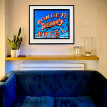 Load image into Gallery viewer, Framed artwork of 'Wonder Wheel' on a wall above a blue sofa artwork by Richard Heeps