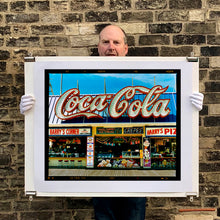 Load image into Gallery viewer, Photograph held by photographer Richard Heeps. Harry's Corner was taken on the wildwood boardwalk, featuring neon typography and the iconic Coca-Cola sign against a bright blue sky. 