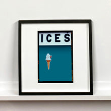Load image into Gallery viewer, Black framed photograph by Richard Heeps.  At the top black letters spell out ICES and below is depicted a 99 icecream cone sitting left of centre against a blue teal coloured background.  
