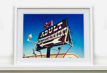 Load image into Gallery viewer, 'Adult Entertainment' photographed in Beatty, Nevada, shows bold typography sitting prominently on an American road sign, against a background of bright blue sky. This fun and cheeky artwork was captured on a road trip through America and features in Richard Heeps' sold out book 'Man's Ruin'. An edition of this artwork recently sold at auction in The Auction Collective exhibition 'Hypercolor-Pop-Culture'.