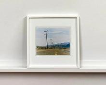 Load image into Gallery viewer, An open road in Amboy, California, featuring telephone poles disappearing into the mountainous distance. This classic and timeless landscape photograph is part of Richard Heeps' 'Dream in Colour' series. 