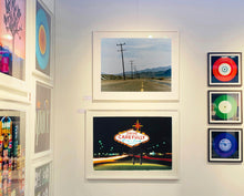 Load image into Gallery viewer, An open road in Amboy, California, featuring telephone poles disappearing into the mountainous distance. This classic and timeless landscape photograph is part of Richard Heeps' 'Dream in Colour' series. 