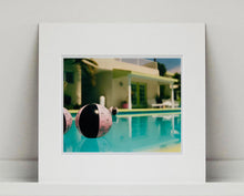 Load image into Gallery viewer, Part of Richard Heeps' 'Dream in Colour' Series, 'Beach Ball' captures Palm Springs mid-century modern architecture behind a trio of pink and black beach balls. The stillness and the subtle colours combine to make a calming artwork with a seductive cinematic vibe.
