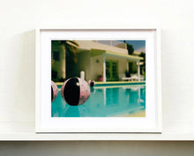 Load image into Gallery viewer, Part of Richard Heeps' 'Dream in Colour' Series, 'Beach Ball' captures Palm Springs mid-century modern architecture behind a trio of pink and black beach balls. The stillness and the subtle colours combine to make a calming artwork with a seductive cinematic vibe.