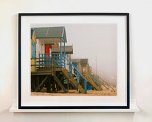 Load image into Gallery viewer, 'Beach Huts', photographed by Richard Heeps in one of his favourite areas of the UK, the port town of Wells-next-the-sea, Norfolk. This piece captures the classic quintessential beach hut on an atmospherically foggy day.