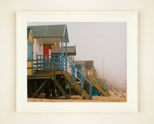 Load image into Gallery viewer, 'Beach Huts', photographed by Richard Heeps in one of his favourite areas of the UK, the port town of Wells-next-the-sea, Norfolk. This piece captures the classic quintessential beach hut on an atmospherically foggy day.