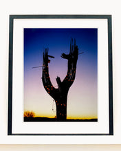 Load image into Gallery viewer, The silhouette of a large scale cactus, dressed in twinkle lights, set against an ombre twilight sky. Photographed by Richard Heeps in the Arizona desert, for his 'Dream in Colour' series.