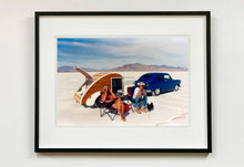 Load image into Gallery viewer, 'Christine's '52 Henry J &amp; teardrop' was captured in Bonneville Salt Flats, Utah, the iconic home of speed. This photograph shows the mountains in the distance meeting and contrasting with the flatness of the salt pan, whilst a pair of retro spectators look out at the speeding cars in the distance.
