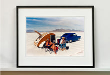 Load image into Gallery viewer, 'Christine's '52 Henry J &amp; teardrop' was captured in Bonneville Salt Flats, Utah, the iconic home of speed. This photograph shows the mountains in the distance meeting and contrasting with the flatness of the salt pan, whilst a pair of retro spectators look out at the speeding cars in the distance.