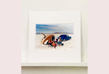 Load image into Gallery viewer, 'Christine's '52 Henry J &amp; teardrop' was captured in Bonneville Salt Flats, Utah, the iconic home of speed. This photograph shows the mountains in the distance meeting and contrasting with the flatness of the salt pan, whilst a pair of retro spectators look out at the speeding cars in the distance.