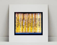 Load image into Gallery viewer, As part of Richard Heeps' series, A Short History of Milan, Delitto A Hollywood features a series of yellow Italian books from a street kiosk. 