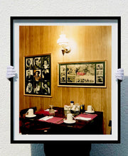 Load image into Gallery viewer, This photograph was taken inside the dining room of the iconic Parry Lodge in Kanab, Utah, which once hosted movie stars of the Western films made in the area. Their faces, cutouts from Life Magazine, adorned the wood panelled walls, which combined with the vintage interior, creates a mid-century cinematic atmosphere. This piece is part of Richard Heeps' 'Dream in Colour' series.