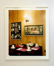 Load image into Gallery viewer, This photograph was taken inside the dining room of the iconic Parry Lodge in Kanab, Utah, which once hosted movie stars of the Western films made in the area. Their faces, cutouts from Life Magazine, adorned the wood panelled walls, which combined with the vintage interior, creates a mid-century cinematic atmosphere. This piece is part of Richard Heeps' 'Dream in Colour' series.