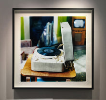 Load image into Gallery viewer, Disc Jockey, photographed by Richard Heeps at Preston Hall Museum, he was commissioned to photograph the museum before it went through regeneration. There is an air of nostalgia in the room of this interior photograph, featuring a retro table-top record player with a Decca vinyl record.