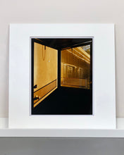 Load image into Gallery viewer, 'Door - Lariat Motel' is a cinematic scene showing a doorway in the glowing evening light, with the setting sun casting shadows across the architecture. Richard Heeps photographed this artwork in Fallon, Nevada whilst on an American road trip. This artwork is part of Richard's 'Dream in Colour' series. 