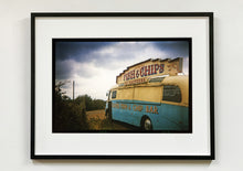 Load image into Gallery viewer, A moody Fenland sky is backdrop to a classic British Fish &amp; Chips Van. The typography and the van itself has a fun fairground feel, contrary to the muted tones of this piece. Part of Richard Heeps series, 'A View of the Fens from the Car with Wings'.