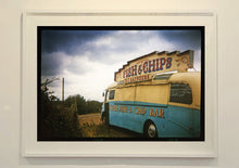 Load image into Gallery viewer, A moody Fenland sky is backdrop to a classic British Fish &amp; Chips Van. The typography and the van itself has a fun fairground feel, contrary to the muted tones of this piece. Part of Richard Heeps series, 'A View of the Fens from the Car with Wings'.