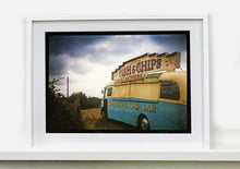 Load image into Gallery viewer, A moody Fenland sky is backdrop to a classic British Fish &amp; Chips Van. The typography and the van itself has a fun fairground feel, contrary to the muted tones of this piece. Part of Richard Heeps series, 'A View of the Fens from the Car with Wings'.