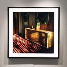 Load image into Gallery viewer, Light streams into the mid-century interior of the Harmony Motel, casting a patterned shadow across the rattan furniture and cactus. This cinematic motel room interior photograph taken in Twentynine Palms, California, is part of Richard Heeps' 'Dream in Colour' series.