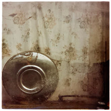 Load image into Gallery viewer, Photograph by Richard Heeps. A hub cap sits in the corner, behind it is a faded brown patterned curtain. 