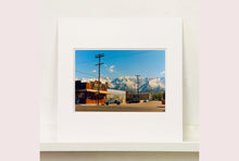 Load image into Gallery viewer, There is a cinematic style to this artwork, 'Lone Pine', taken in a former movie town in California where many Western films were made. Taken outside Richard's iconic interior photograph 'Bonanza Café', set in the Owens Valley against a mountainous  backdrop.