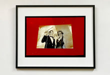 Load image into Gallery viewer, 'Magic Act' is a sepia toned vintage image laid on a bright red backdrop. This photograph was captured at the Red Lodge, a stop often used by performers as they traveled across the country.