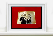 Load image into Gallery viewer, 'Magic Act' is a sepia toned vintage image laid on a bright red backdrop. This photograph was captured at the Red Lodge, a stop often used by performers as they traveled across the country.
