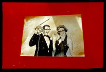 Load image into Gallery viewer, 'Magic Act' is a sepia toned vintage image laid on a bright red backdrop. This photograph was captured at the Red Lodge, a stop often used by performers as they traveled across the country.