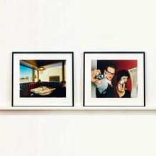Load image into Gallery viewer, A couple look into the camera in burlesque costume against a red wall. Contemporary portrait photography by Richard Heeps framed in black