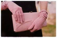 Load image into Gallery viewer, Photograph by Richard Heeps.  Pink clutch bag being held by matching pink gloved hands, set against the wearer's black dress.