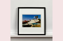 Load image into Gallery viewer, A vintage parasol, poolside at the El Morocco Motel, Las Vegas, Nevada, overlooked by palm trees, blue skies and iconic neon signs. Part of Richard Heeps' 'Dream in Colour' series.