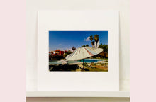 Load image into Gallery viewer, A vintage parasol, poolside at the El Morocco Motel, Las Vegas, Nevada, overlooked by palm trees, blue skies and iconic neon signs. Part of Richard Heeps' 'Dream in Colour' series.
