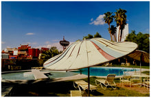 Load image into Gallery viewer, A vintage parasol, poolside at the El Morocco Motel, Las Vegas, Nevada, overlooked by palm trees, blue skies and iconic neon signs. Part of Richard Heeps' 'Dream in Colour' series.