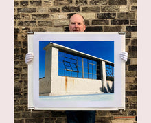 Load image into Gallery viewer, 'Window of the World, Zzyzx Resort Pool', photographed in Soda Dry Lake, California shows window pains and a distressed wall, against a bright blue background of sky. This artwork is part of Richard's 'Dream in Colour' series. 