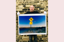 Load image into Gallery viewer, Part of Richard Heeps' 'Dream in Colour' Series, this beautiful picture taken at dusk captures the sunset in the valley.  It was photographed in what was once a goldmine, now a ghost town. The 5MPH sign seems so cautious, but on closer inspection you see that it is peppered with bullet holes, serving as a reminder of its Western past. 