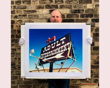 Load image into Gallery viewer, 'Adult Entertainment' photographed in Beatty, Nevada, shows bold typography sitting prominently on an American road sign, against a background of bright blue sky. This fun and cheeky artwork was captured on a road trip through America and features in Richard Heeps' sold out book 'Man's Ruin'. An edition of this artwork recently sold at auction in The Auction Collective exhibition 'Hypercolor-Pop-Culture'.