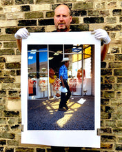 Load image into Gallery viewer, 'Boutique' is street portrait, taken in Palm Springs, California. This piece is different from Richard Heeps' usual style, but everything fell into place: the light, the colours, and the man walking through the shot.