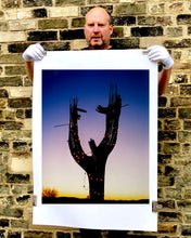 Load image into Gallery viewer, The silhouette of a large scale cactus, dressed in twinkle lights, set against an ombre twilight sky. Photographed by Richard Heeps in the Arizona desert, for his 'Dream in Colour' series.