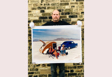 Load image into Gallery viewer, 'Christine's '52 Henry J &amp; teardrop' was captured in Bonneville Salt Flats, Utah, the iconic home of speed. This photograph shows the mountains in the distance meeting and contrasting with the flatness of the salt pan, whilst a pair of retro spectators look out at the speeding cars in the distance.