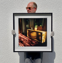 Load image into Gallery viewer, Light streams into the mid-century interior of the Harmony Motel, casting a patterned shadow across the rattan furniture and cactus. This cinematic motel room interior photograph taken in Twentynine Palms, California, is part of Richard Heeps' 'Dream in Colour' series.