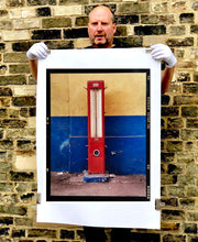 Load image into Gallery viewer, A red retro tyre pump against a yellow and blue painted wall, in the Porta Genova area of Milan. 